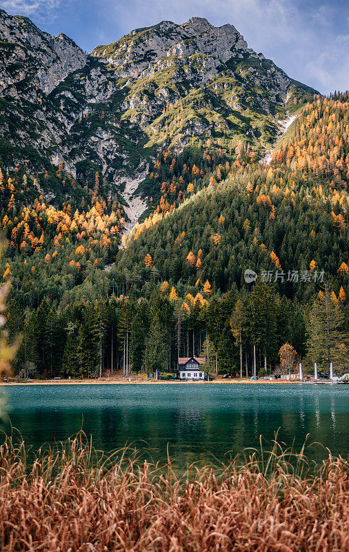 Dobbiaco湖(Toblacher See)的景观视图，在意大利南蒂罗尔的白云石，有一个舒适的小屋，映着绿松石色的水和多彩的森林